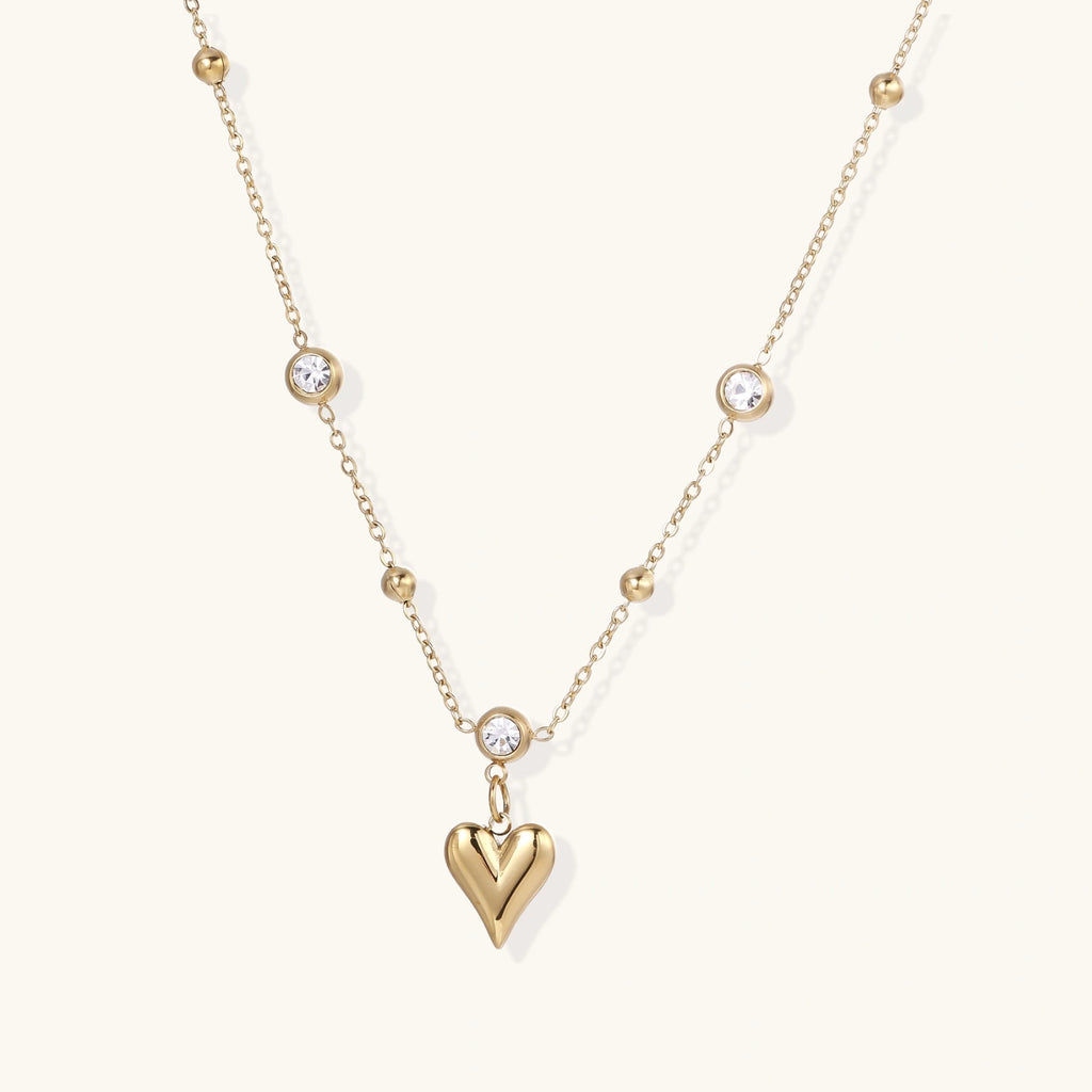 Crystal Heart Charm Necklace in gold with crystals on a plain background