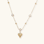 Crystal Heart Charm Necklace in gold with crystals on a plain background