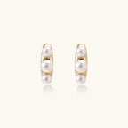 14K gold-plated curved stud earrings with three white freshwater pearls aligned vertically on cream background
