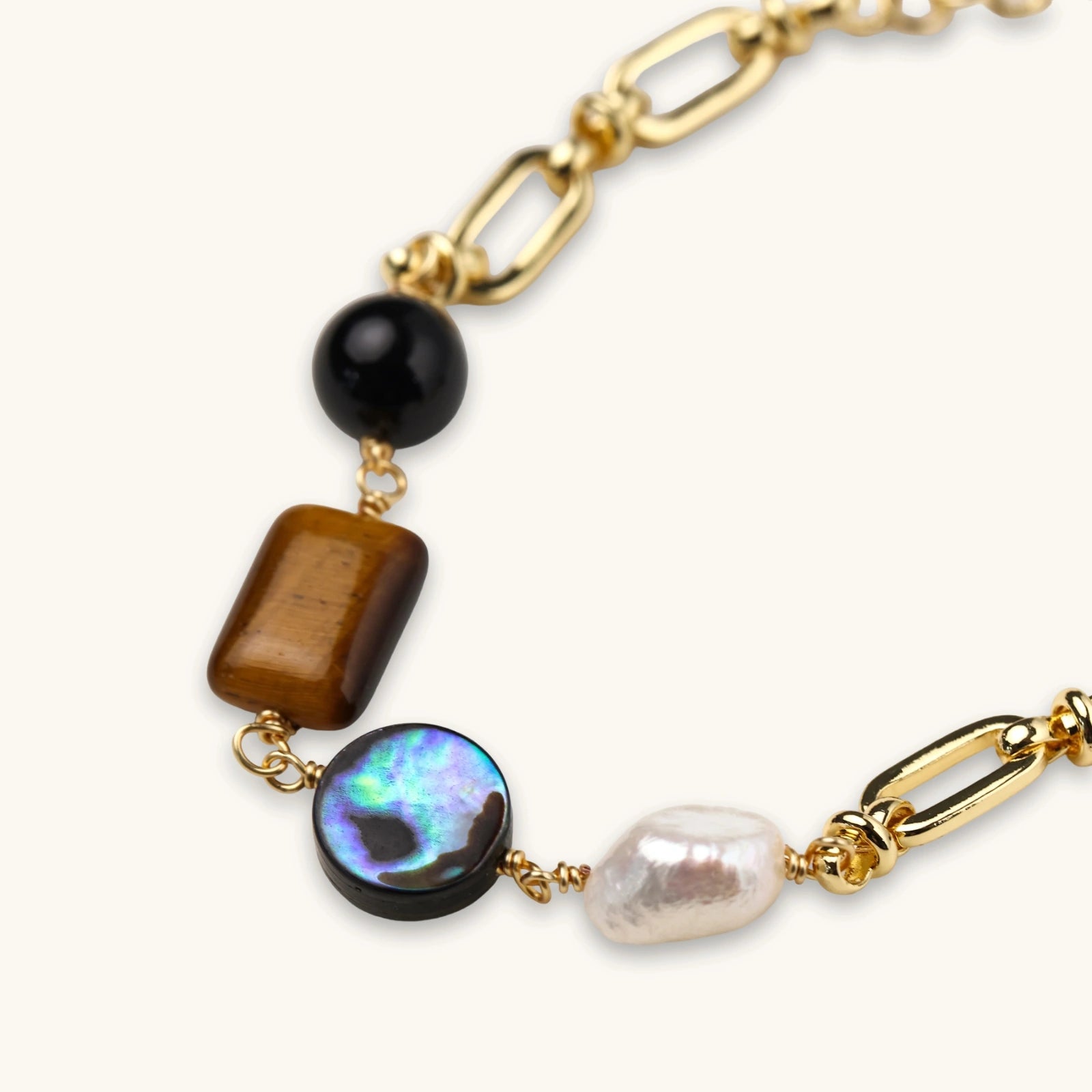 Earth Elements Bracelet gold chain with black, brown, abalone, and pearl stones on white background